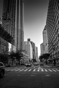 City street by modern buildings against sky