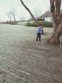 Full length of man standing on bare tree