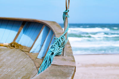 Close-up of rope tied on wood against sky