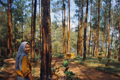 Side view of man standing by trees in forest