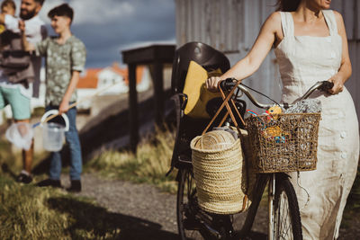 Midsection of woman with bicycle while family standing in background on archipelago