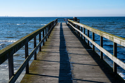 Wooden pier over sea against sky