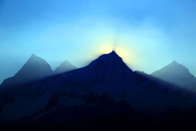 Silhouetted mountain peak against blue sky