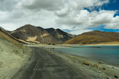 Scenic view of road by mountains against sky