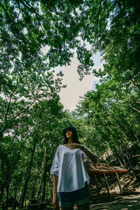 Rear view of woman standing against trees in forest