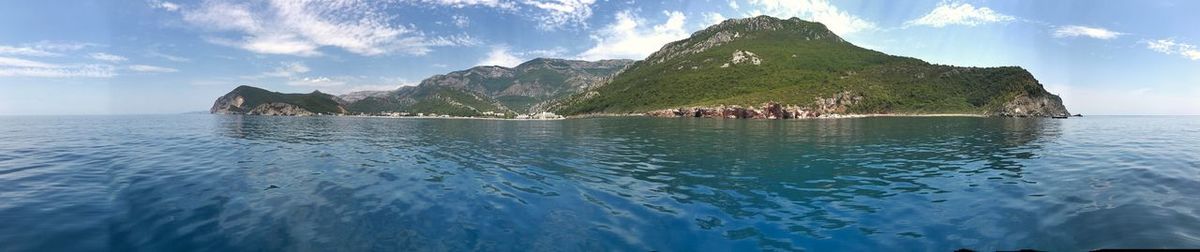 Scenic view of sea by mountains against sky