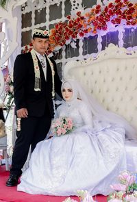 Rear view of couple holding hands by flowers