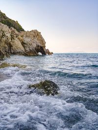 Scenic view of rocks in sea against clear sky