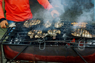 Seller is processing grilled fish that is still on the grill 