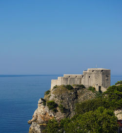 Building by sea against clear blue sky