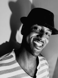 Portrait of smiling man wearing hat while standing against wall