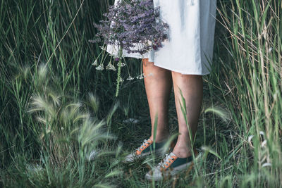 Serene girl's legs in sneakers amidst nature's field, bouquet of flowers