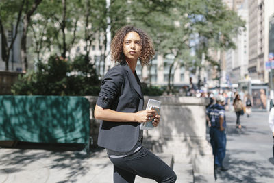 Full length of woman holding smart phone in city