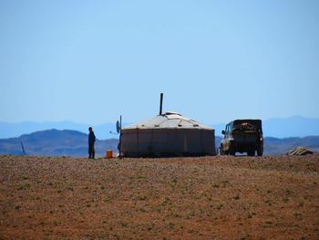 Tent by jeep on field against clear sky