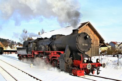 Train on railroad tracks against sky during winter