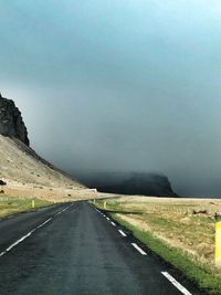 Empty road by mountain against sky