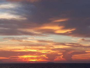 Scenic view of sea against dramatic sky during sunset