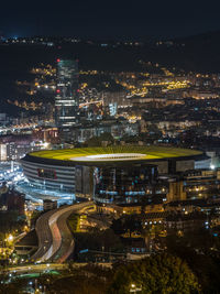 High angle view of illuminated street amidst buildings in city at night