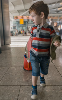 Full length of innocent boy with toy on floor at airport