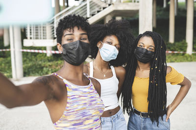 Young women wearing protective face masks taking selfie during pandemic