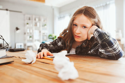 Portrait of girl sitting by table at home