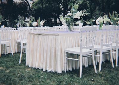 Empty chairs and table against trees in yard