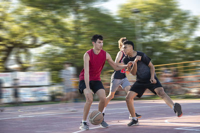 Group of teenagers playing street basketball