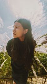 Portrait of young woman looking away against sky