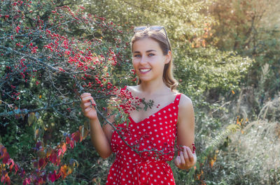 Young woman near bush with red hawthorn berries. smile, natural beauty