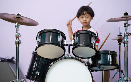 Full length of child sitting drum on stage