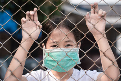 Little girl wearing medical protective mask in cage. quarantine for protect coronavirus.