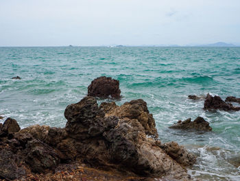 Rocks on shore by sea against sky