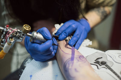 High angle view of artist making tattoo on hand