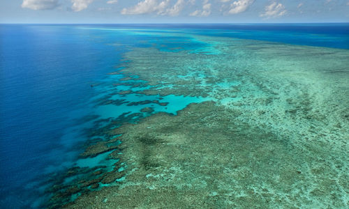 Scenic view of great barrier reef and turquoise sea against blue sky