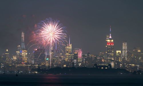 Firework display over illuminated buildings in city at night