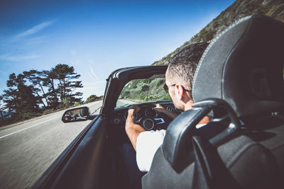 Portrait of man driving car against road