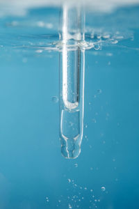 Pipette with cosmetic product in water with bubbles.