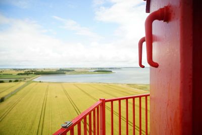 Red railing by sea against sky