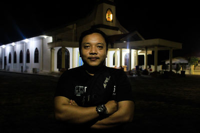 Portrait of young man standing in front of building