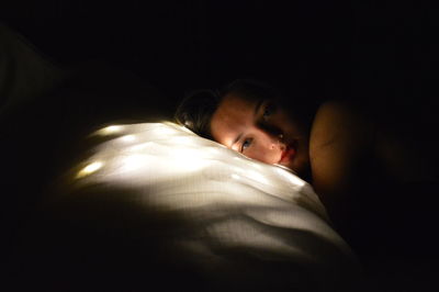 Portrait of woman lying on bed at room