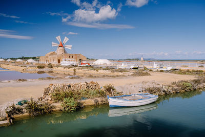 Traditional windmill by water against sky