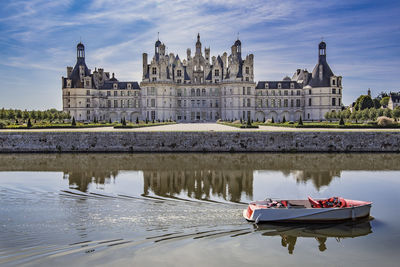 Reflection of building in lake against cloudy sky