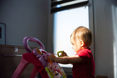 Baby play and learn on baby tablet on weels against bright window. child development concept