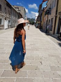 Rear view of woman walking on footpath in city