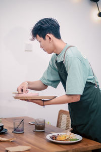 Side view of young man working at table