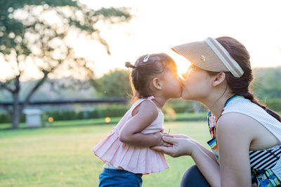 Mom and daughter kissing each other on the lips at park. mother day concept