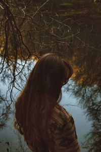 Rear view of woman standing against bare tree