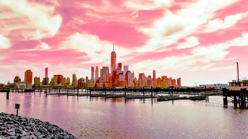 City at waterfront against cloudy sky