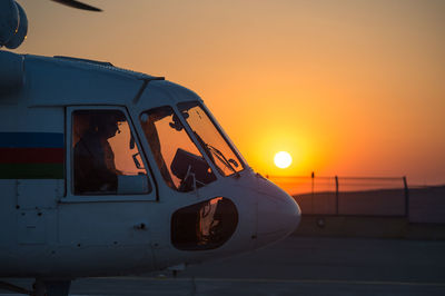 Helicopter on runway against sky during sunset