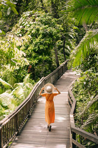 Rear view of woman walking on footbridge